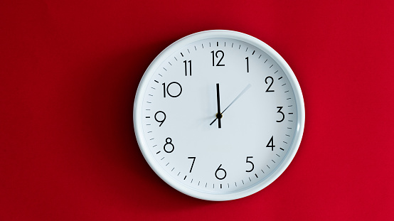White wall clock on red background.