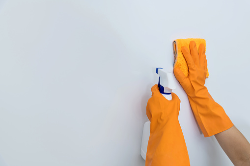 Woman hand cleaning white wall with rag.