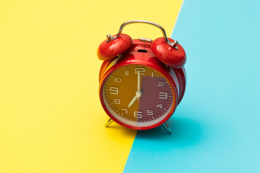 Red alarm clock on colored background.