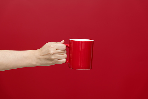 Human hand holding a red mug.