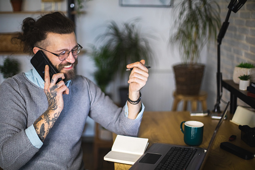 Happy businessman having a phone call while working at home office