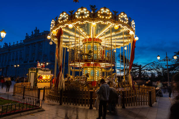 A crowd watching a illuminated bunk carrousel in Madrid Madrid, Spain 27-12-2023 A crowd watching a illuminated bunk carrousel during blue hour in the centre of Madrid during Christmas season named animal stock pictures, royalty-free photos & images
