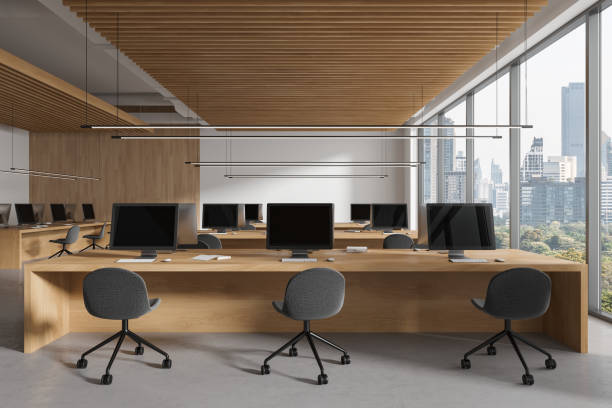 istock Modern coworking interior with chairs, pc monitors on table in row near window 1917049338