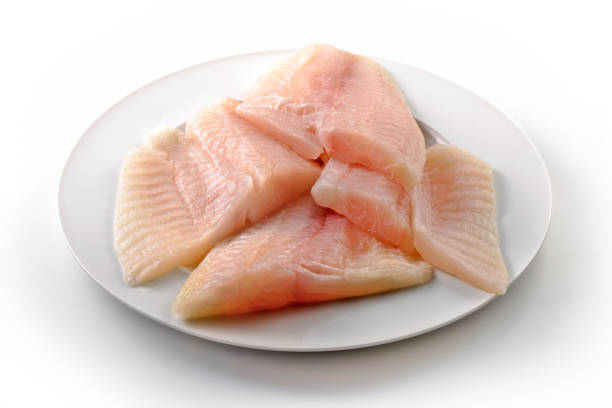 Round white plate with raw fish fillets isolated on white background