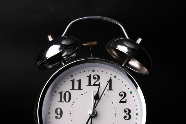primo piano di una sveglia retrò su sfondo nero. le lancette dell'orologio si muovono velocemente, l'inizio del tempo è alle 12:00 o alle 12:00. - alarm clock clock clock face time foto e immagini stock