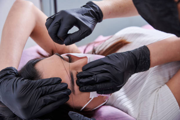 istock Beauty salon worker treading a client's eyebrows 1917054928