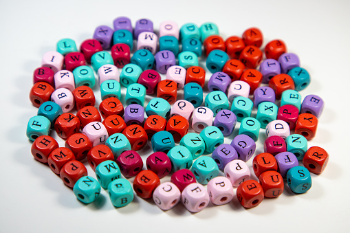 An array of colorful cubic beads with letters on a white background