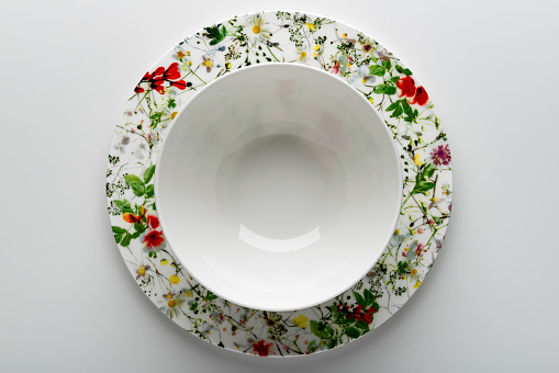 Top view of White empty teacup with plate decorated with painted flowers isolated on white background