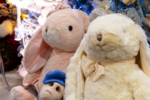 Plush toy bunnies on the background of a Christmas tree.