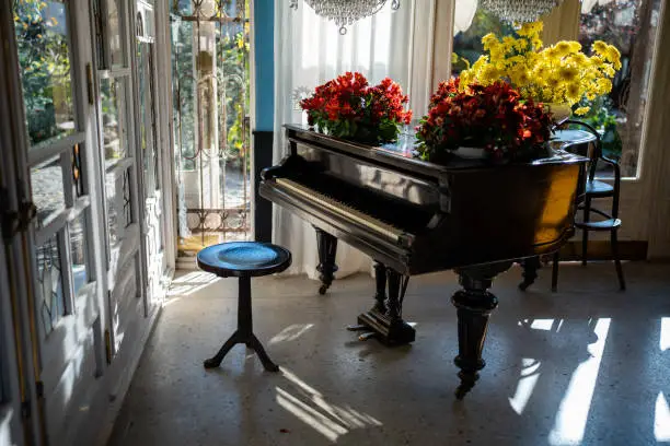Vintage interior of classic style music room with grand piano, big window, luxury chandelier. Apartment used for performance and listening of musical compositions, vocal practice, singing, relaxation