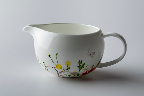 Milk jug decorated with painted flowers isolated on white background
