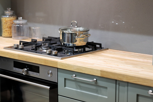 Wooden kitchen countertop with hob gas stove. Selective focus.