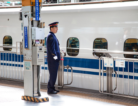 7th April 2012 - Osaka, Japan\nShinkansen N700 bullet train at a train station with station staff on the platform.