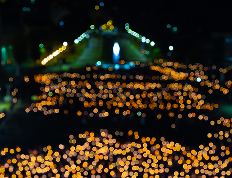 Intentionally blurred crowd of pilgrims with lighted candles praying in a night pilgrimage procession in Lourdes.