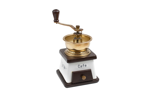 Old coffee grinder with small cofee beans at side and white background