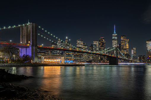 View of the Brooklyn Bridge at night and the carousel, long exposure photograph. Brooklyn carousel. New york sky line. Lights of buildings. New york at night.