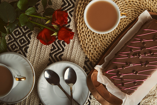 Valentine's day festive breakfast with cherry chocolate cake, coffee cups and aesthetic background of red roses.
