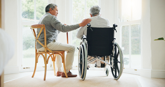 A senior woman walking down a corridor with the assistance of a walker. view from rear