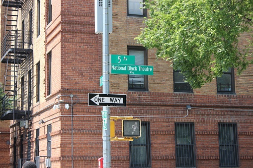 Green New York City street signs for 5th Avenue aka National Black Theatre Way on the corner of W 126th Street near the National Black Theatre building in Harlem, New York