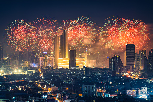 Beautiful annual happy new year festival with firework display glowing over iconic department store, illuminated building in downtown during midnight time at Bangkok, Thailand