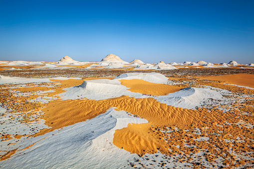 Nature landmarks of wildlife in Western Sahara with white stone relief and yellow sand in front. Sahara el Beyda, the White Desert Protected Area, is a national park in Egypt, first established as a protected area in 2002. It is located in the Farafra depression, 45 km (28 mi) north of the town of Qsar El Farafra. Part of the park is in the Farafra Oasis (New Valley Governorate). The park is the site of large white chalk rock formations, created through erosion by wind and sand. It is also the site of cliffs (at the northern end of the Farafra Depression), sand dunes (part of the Great Sand Sea), as well as Wadi Hennis and oases at Ain El Maqfi and Ain El Wadi.
