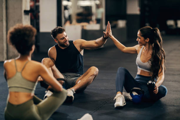 istock Group of three fit friends giving high five after exercise while sitting on a gym floor. 1917190511