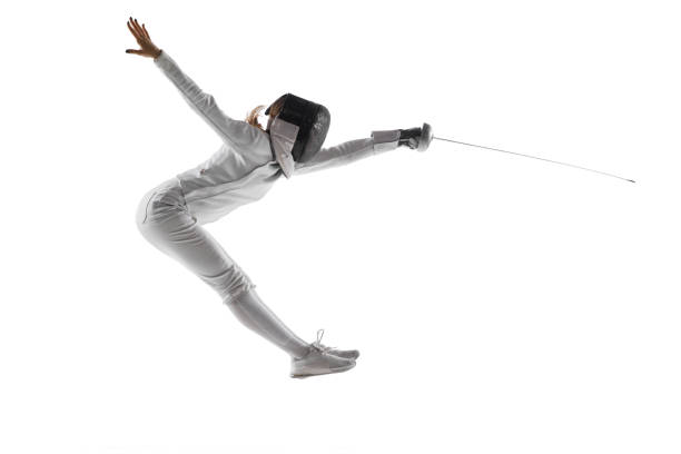 istock Dynamic portrait of swordswoman in mid-air, focus on determined attack against white studio background. Spirit of dedication and victory. 1917191047