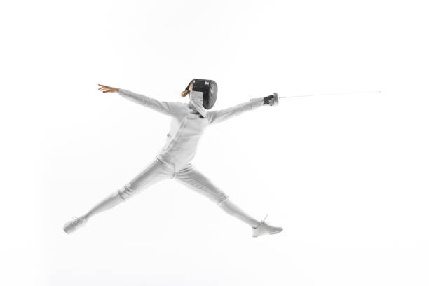istock Female fencer's posing in mid-air, in jump sword held high, against white studio background. Sense of victory and accomplishment. 1917191083