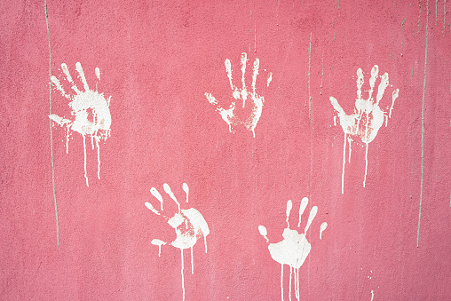 white painted handprints on pink concrete wall