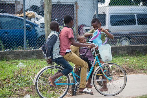 Aneho, Togo - November 20, 2019: Cyclist on the highway passing an illegal black market petrol station, which offers petrol in bottles and in a yellow container on the roadside. Location: N2 close to Church Paroisse Catholique Sacre-Coeur de Jesus Adjido in Aneho, Togo, West Africa.