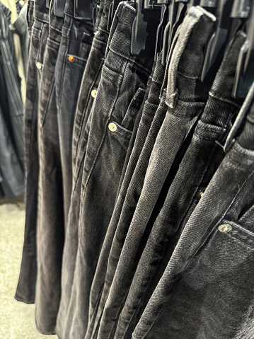 Stock photo showing department store clothes display of black denim jeans on clothes rail in women's clothing section.