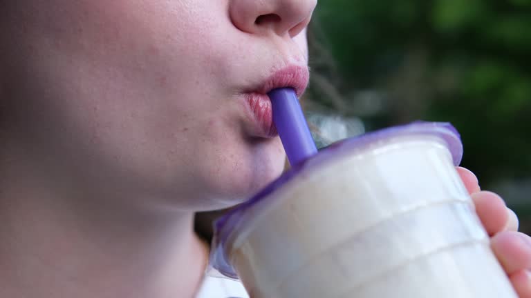 Delicious drink Bubble Tea drinking delicious coffee tea smoothie on the street a young girl happily pulls liquid from a straw chews swallows yami yami.