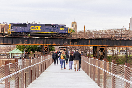 Richmond, Virginia, USA - February 11, 2023 - A CSX Locomotive pulls a coal and freight train on the north bank of the James River as seen from the T. Pottersfield Bridge