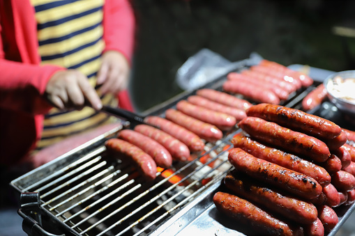 Grilling Meat on barbecue grill with hot coal. Grilled sausages are a common and affordable roadside snack in Taiwan. Sausage is made from ground pork. Taiwanese people like to eat raw garlic with sausage. 
Sausages are carcinogens and are not recommended to be eaten too often.