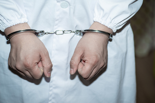 Doctor in handcuffs wearing Lab Coat
