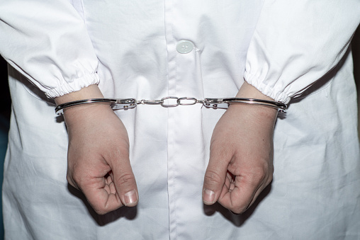 Doctor in handcuffs wearing Lab Coat
