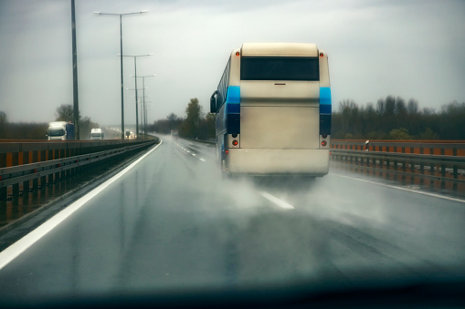 View form a car of a bus driving on a highway rainy weather.