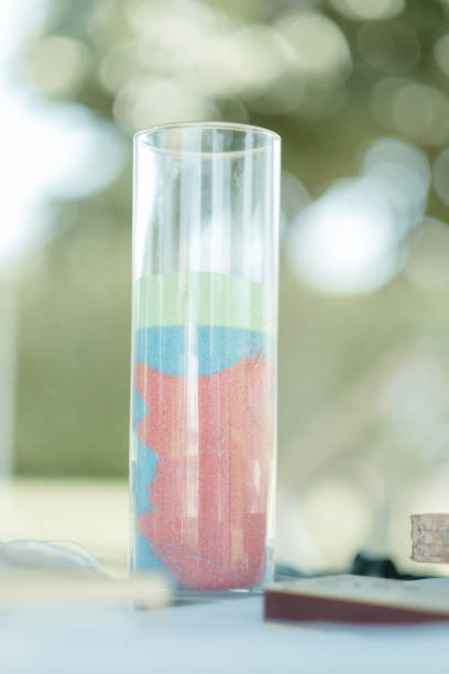 A close-up shot of a laptop computer placed on a surface with a glass jar containing multiple colors of sand beside it