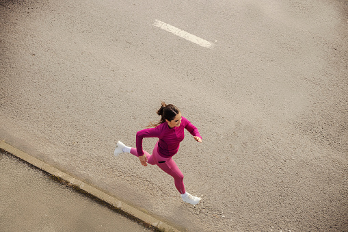From above view of a fast sportswoman in shape running on driveway.