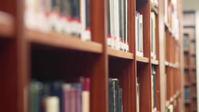 A book is being picked from a bookshelf, shallow focus stock video