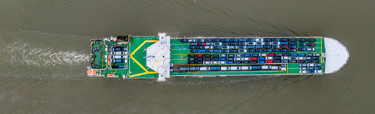 Aerial photos from a drone of a boat transporting brand new cars along the River Thames at Rainham, Essex, UK.