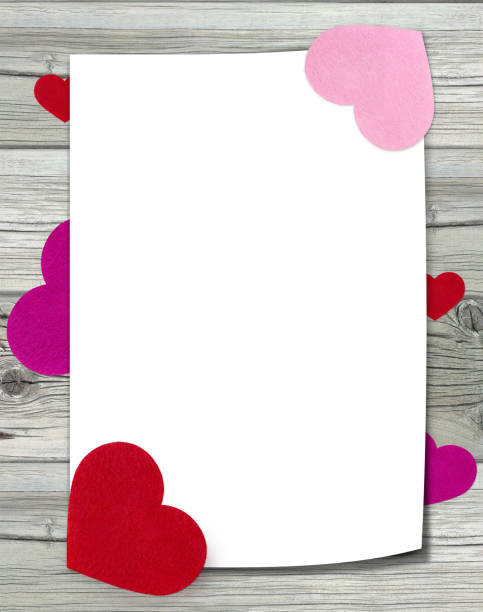 istock White sheet of paper with felt hearts on wooden background. 1917456607