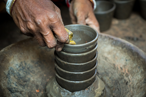Pottery making involves shaping clay by hand, using a wheel, or coiling techniques. Artists mold and sculpt the clay, creating functional or decorative pieces. After shaping, the pottery is dried by fire and sunshine and often glazed for a final touch. This image was captured from Saver, Bangladesh on December 29, 2023.