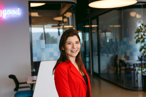 Portrait of young business woman smiling and look at camera posing with crossed arms in a creative luxury office with copy space area. XXXL size