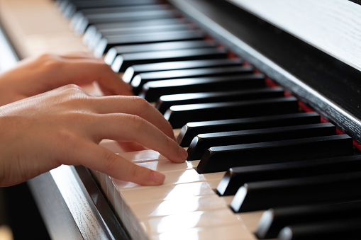 Close up of the hands of a girl playing the piano.