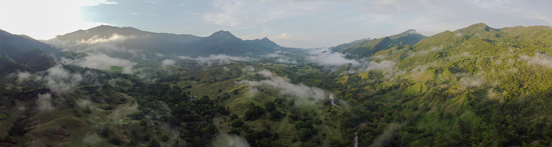 An panoramic impressive time of fog passing through the mountains and rainy weather in Colombia during sunrise. cloudy sky drone between the clouds