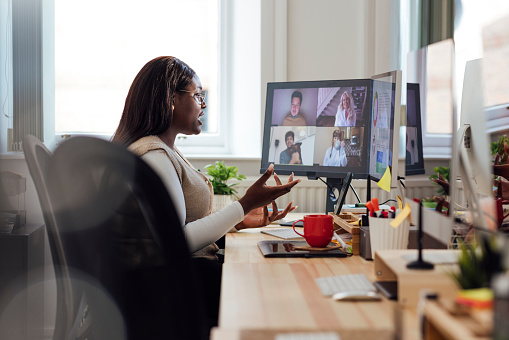 A side view of a manager speaking to her staff who are working from home. She is having a team briefing and getting up to date with everyones progress. She is working in her office in Newcastle Upon Tyne in the North East of England.