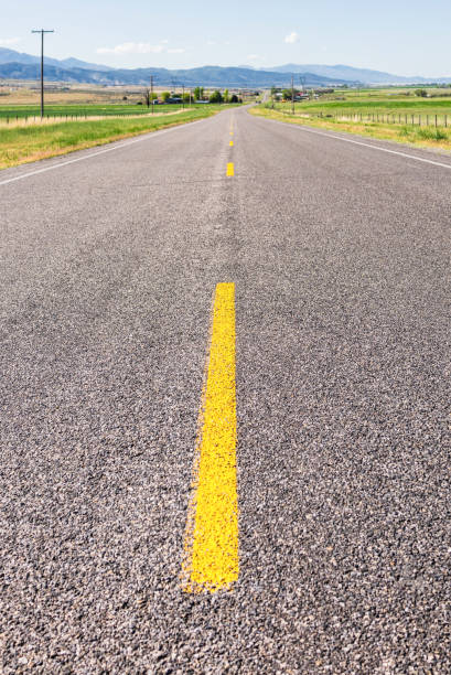 Middle of the rural highway Close up on the road marking and surface in the foreground as a rural highway in Utah stretches out into the distance. single yellow line sunlight usa utah stock pictures, royalty-free photos & images