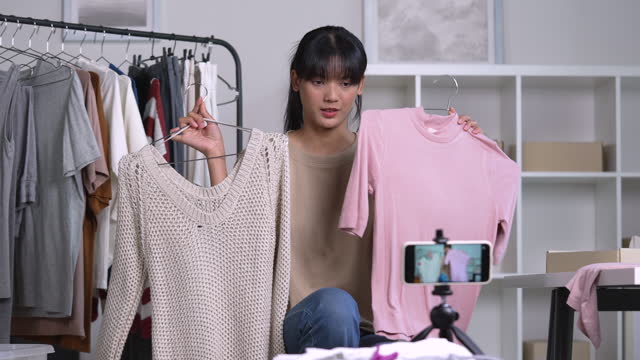 Young Asian woman blogger or vlogger looking at camera reviewing product. Young Asian female online seller using social media for marketing. Business online influencer, Side hustle concept.