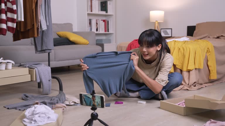 Young Asian woman blogger or vlogger looking at camera reviewing product. Young Asian female online seller using social media for marketing. Business online influencer, Side hustle concept.